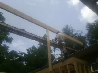 Carpenter setting a ridge beam over a new addition frame — Ice Dam Removal by Roofing Brothers in Driftwood