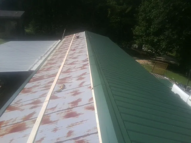 Old rusted panels beside newly installed green metal roofing — Wind Damage Roof Repair by Roofing Brothers in Driftwood