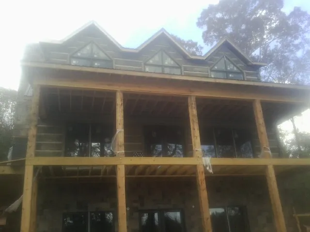 Dormers and porch framing on a large log home under construction — Roof Coating work by our crew in Driftwood