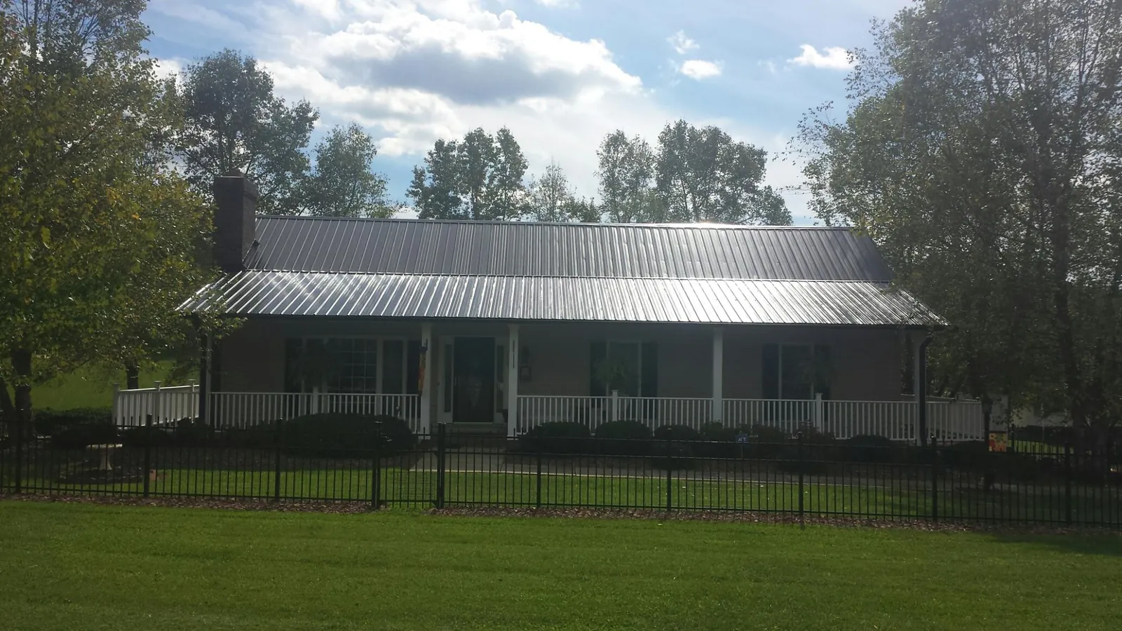 Gray metal roof on a brick ranch with a full width front porch — Gutter Guard Installation work by our crew in Driftwood