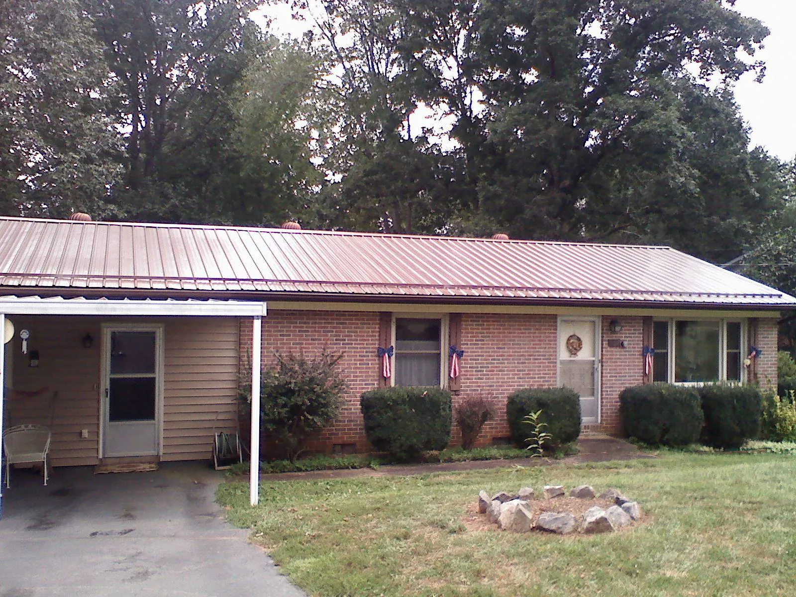 Bronze metal roof and carport on a brick ranch home — Roof Repair work by our crew in Driftwood