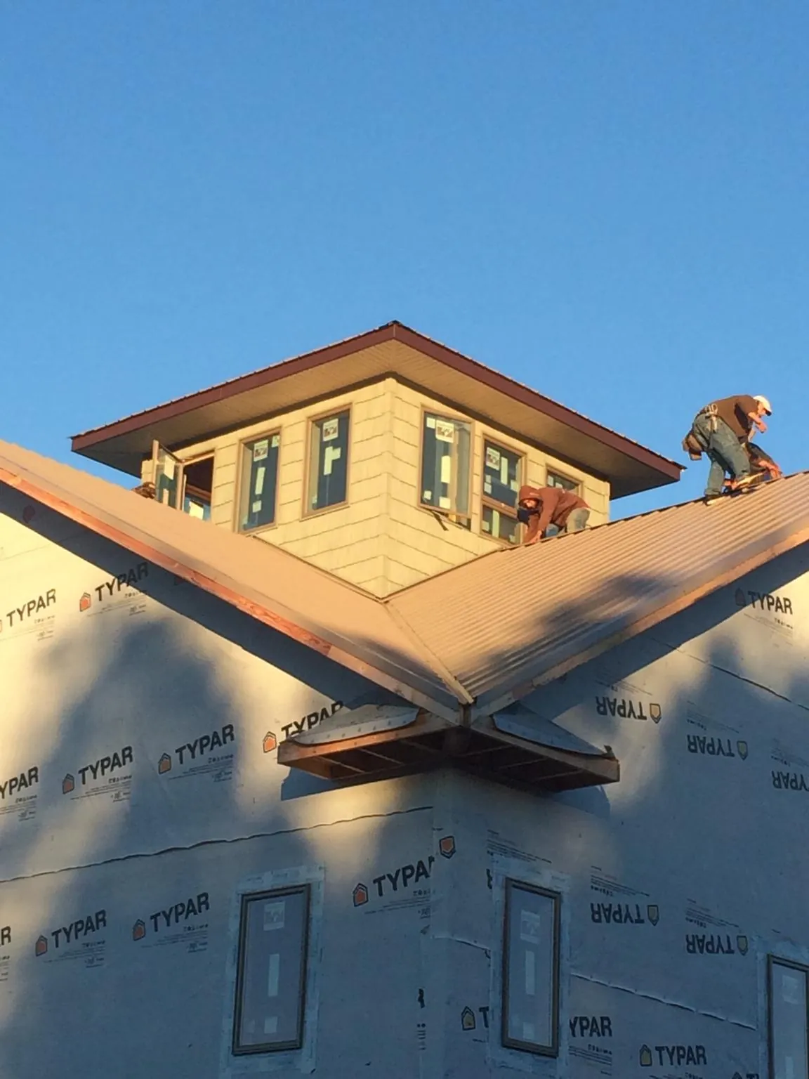 Roofers working around a rooftop cupola on a new metal roof at sunset — Roof Waterproofing in Driftwood by Roofing Brothers